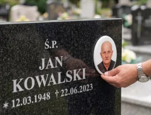 Gdzie umieścić zdjęcie na nagrobku? Ręka przykładająca zdjęcie do nagrobka z danymi osobowymi w celu ustalenia miejsca montażu fotografii nagrobnej